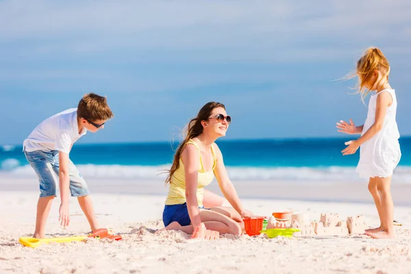 母亲和孩子做沙子城堡在地处热带的海滩 — 图库照片