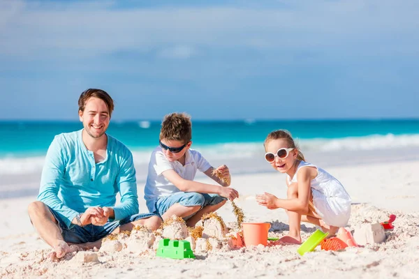 父亲和孩子们玩沙滩上的沙子 而享受暑假 — 图库照片