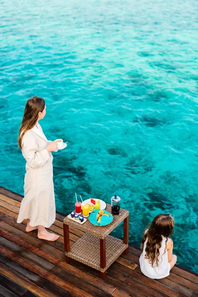 母亲和女儿在享受海景水上别墅酒店吃早饭时的木码头 — 图库照片