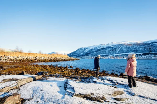 愛らしい少女と屋外北ノルウェーのフィヨルドに囲まれたビーチで雪に覆われた冬の日を楽しむかわいい男の子 — ストック写真