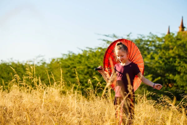 ミャンマー バガンの古代寺院を訪問伝統的なビルマの日傘を持つ少女 — ストック写真