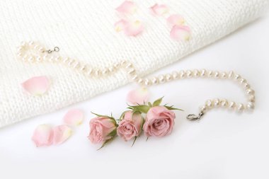 Güller ve beyaz zemin üzerine inciler