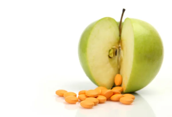 Manzana verde y pastillas sobre un fondo blanco — Foto de Stock