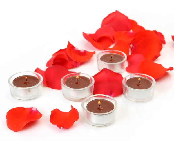 Petals of scarlet roses and candles — Stock Photo, Image
