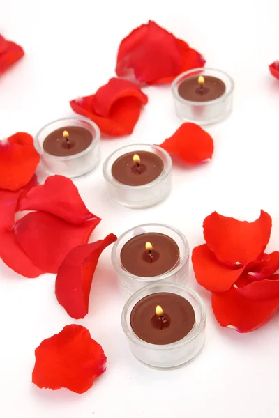 Bloemblaadjes van scarlet rozen en kaarsen — Stockfoto