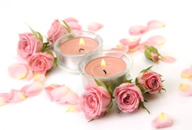 Güller ve beyaz zemin üzerine mumlar