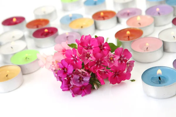 Barevné hořící svíčky a růžové květy — Stock fotografie