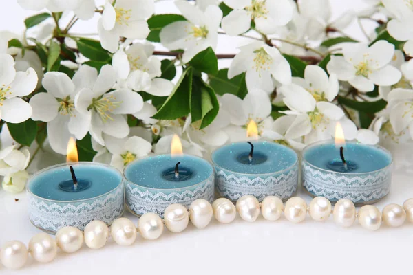 Perles de perles, bougies allumées et branches de pommier en fleurs — Photo