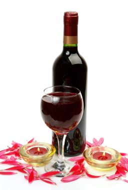 Beyaz arka planda şarap ve taç yaprakları olan şişe.