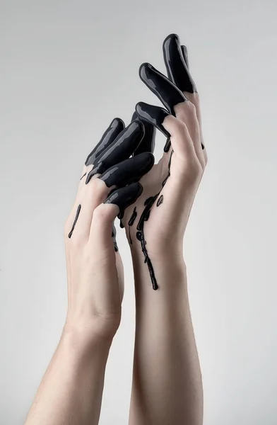 Female hand in black oil — Stock Photo, Image