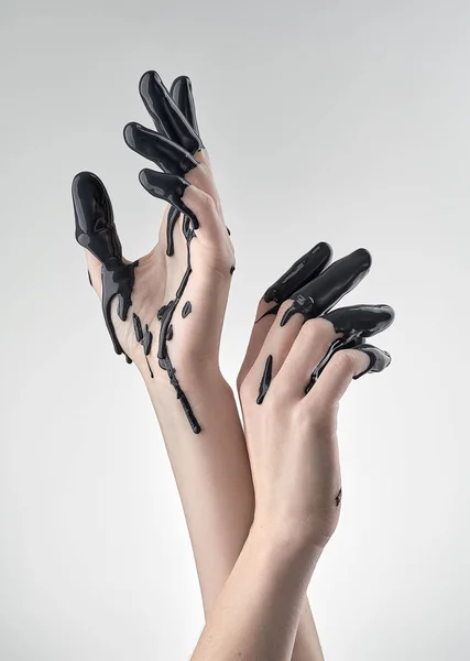 Weibliche Hand in schwarzem Öl — Stockfoto