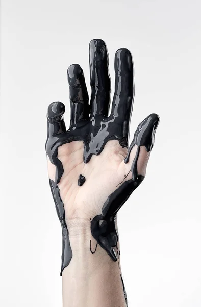 Mão feminina em óleo preto — Fotografia de Stock