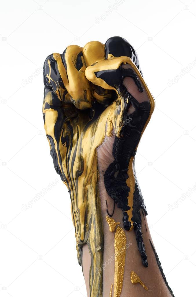 Female hand in liquid black and golden oil