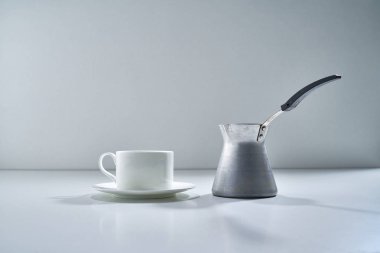 Açık gri arka planda beyaz porselen çay takımı ve narin bir buket çiçekle kompozisyon