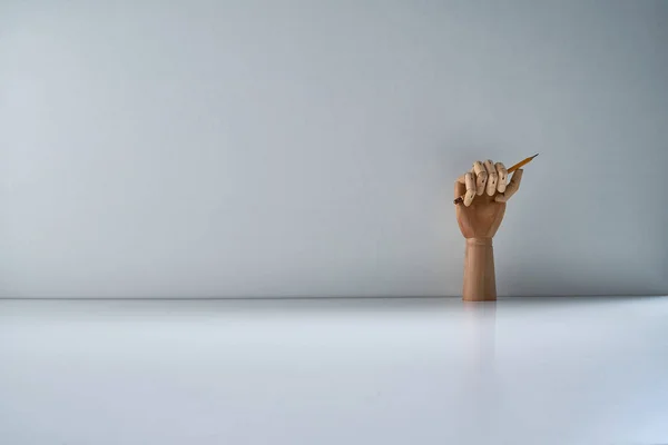 灰色の背景に鉛筆で木製の手 — ストック写真