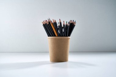 Gri arka planda kahverengi bir karton standı çizmek için çok renkli kalemler