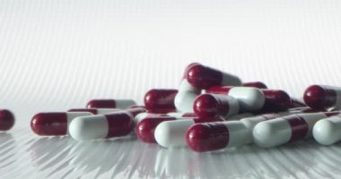 Beyaz-kırmızı haplar arka planda zıt yönlere düşüp yuvarlanıyor