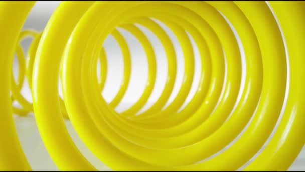 Salida Suave Una Espiral Plástico Amarillo Sobre Fondo Gris Claro — Vídeos de Stock