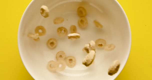 Złote Pyszne Pierścienie Płatków Śniadaniowych Spadają Białym Kubku Jasnożółtym Tle — Wideo stockowe