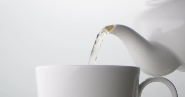Чай Наливают Белого Керамического Чайника Белый Керамический Стакан Светлом Фоне — стоковое видео