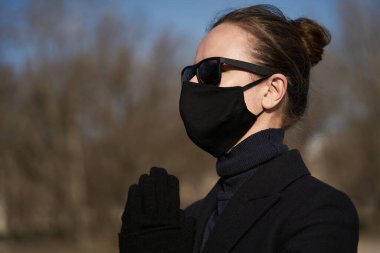 Siyah koruyucu maskeli ve siyah güneş gözlüklü genç kız, virüse karşı korunuyor.