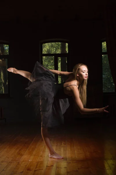 Unga ballerina i ett mörkt rum — Stockfoto