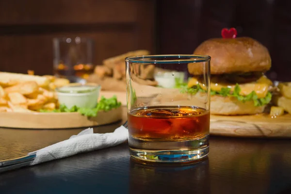 Burger ve bardak viski ahşap plakalar üzerinde — Stok fotoğraf