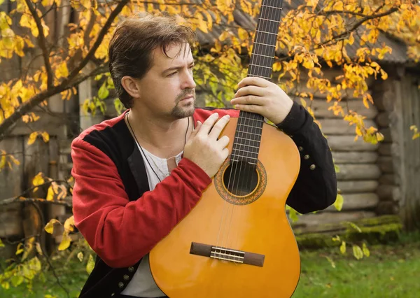 Člověk hraje na kytaru v podzimní zahradě — Stock fotografie