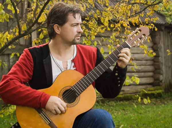 Hombre tocando la guitarra en el jardín de otoño —  Fotos de Stock