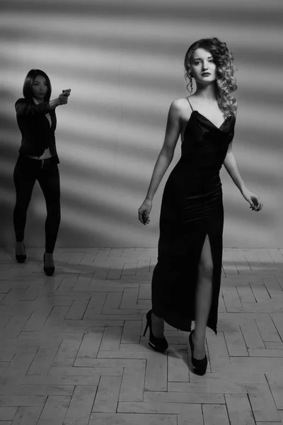 Hitwoman con un arma amenazando a la joven hermosa chica — Foto de Stock