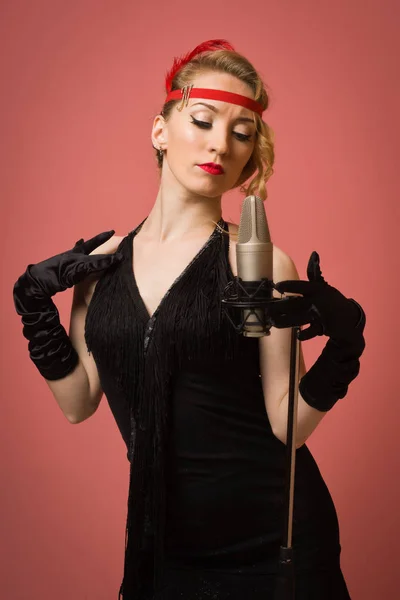 Krásná herečka v černé retro šaty zpěv s mikrofonem — Stock fotografie