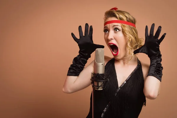 Pretty actress in black retro dress singing with microphone — Stock Photo, Image