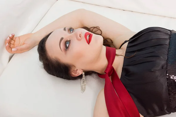 Přidušeným krásná žena v černých šatech leží na gauči — Stock fotografie