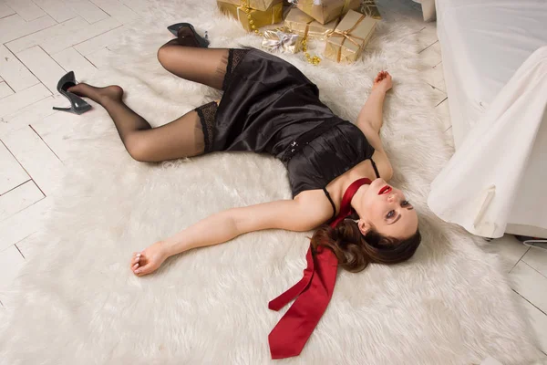 Přidušeným krásná žena v černých šatech leží poblíž vánoční — Stock fotografie