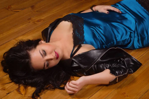 Ung kvinna klädd i korta spets klänning lögner på ett golv — Stockfoto