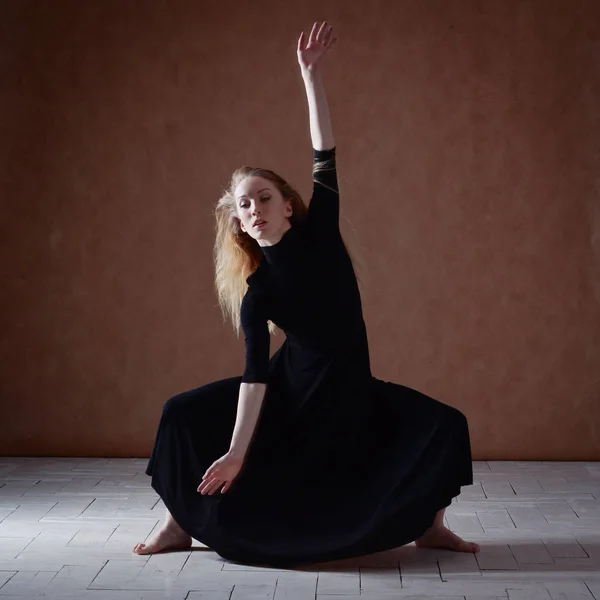 Modern ballet dancer posing on dark background