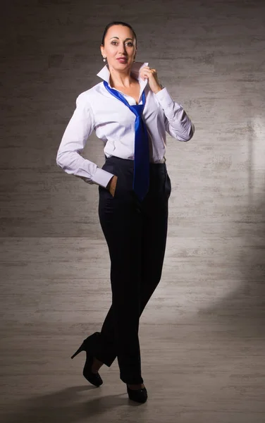 Mujer de negocios vestida con pantalones, blusa blanca, corbata posando en una — Foto de Stock