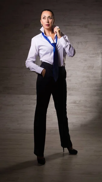 Деловая женщина, одетая в брюки, белая блузка, галстук, позирующий на — стоковое фото