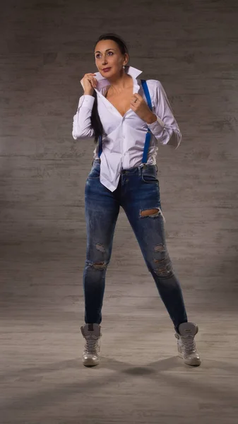 Adulto bella donna vestita in jeans, una camicetta bianca in posa su un — Foto Stock