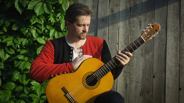 Uomo adulto che suona la chitarra nel giardino estivo — Foto Stock