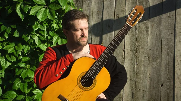 Hombre adulto tocando la guitarra en el jardín de verano — Foto de Stock