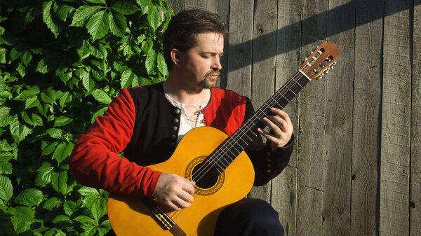 Adult man playing guitar in summer garden