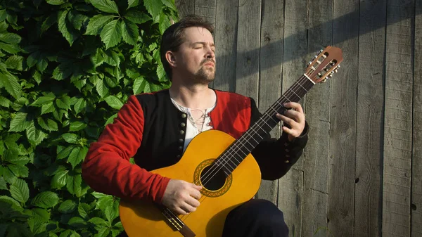 Hombre adulto tocando la guitarra en el jardín de verano — Foto de Stock