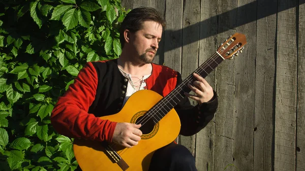 Adult man playing guitar in summer garden — Stock Photo, Image