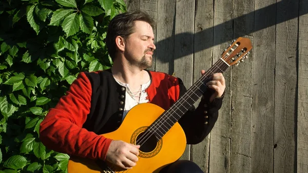 Hombre adulto tocando la guitarra en el jardín de verano — Foto de Stock