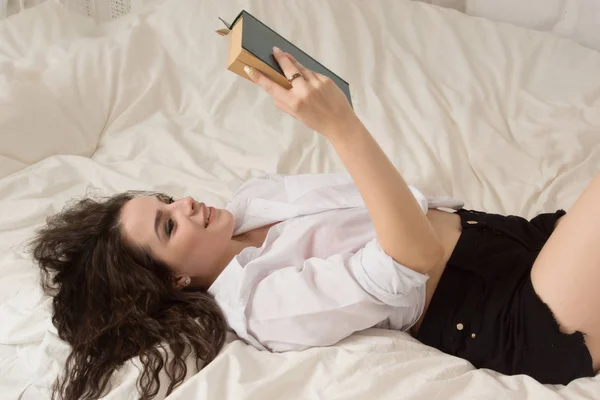 Dívka je čtení knihy v posteli — Stock fotografie