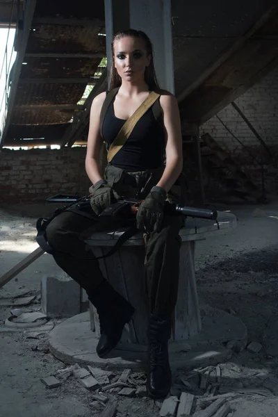 Девушка с пистолетом на заброшенной фабрике — стоковое фото