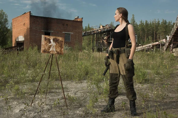 Flicka med en pistol i en övergiven fabrik — Stockfoto