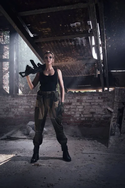 Chica con un arma en una fábrica abandonada — Foto de Stock