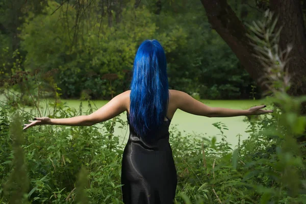 Hermosa mujer con cabello azul oscuro vestida con vestido negro en th —  Fotos de Stock